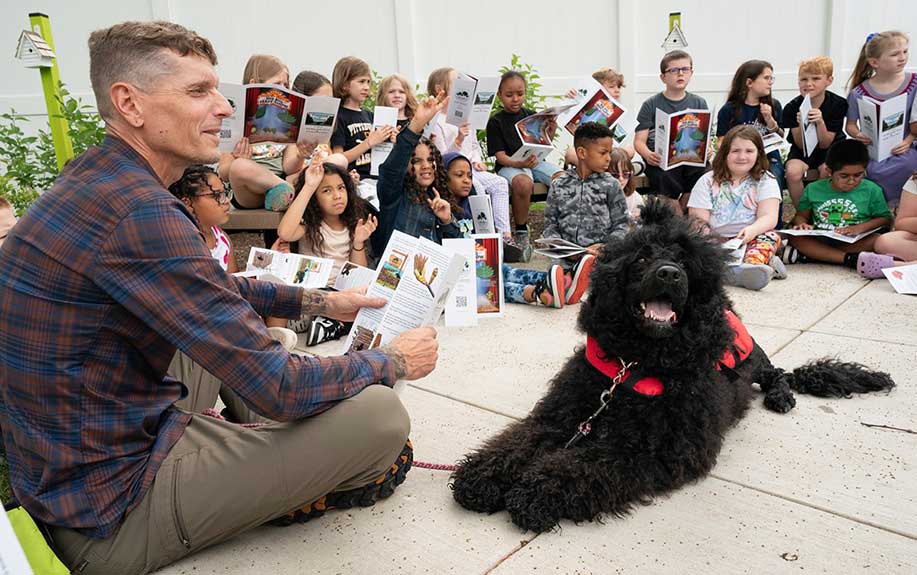 Jeff Karwoski and his dog, Forest, sitting with children reading